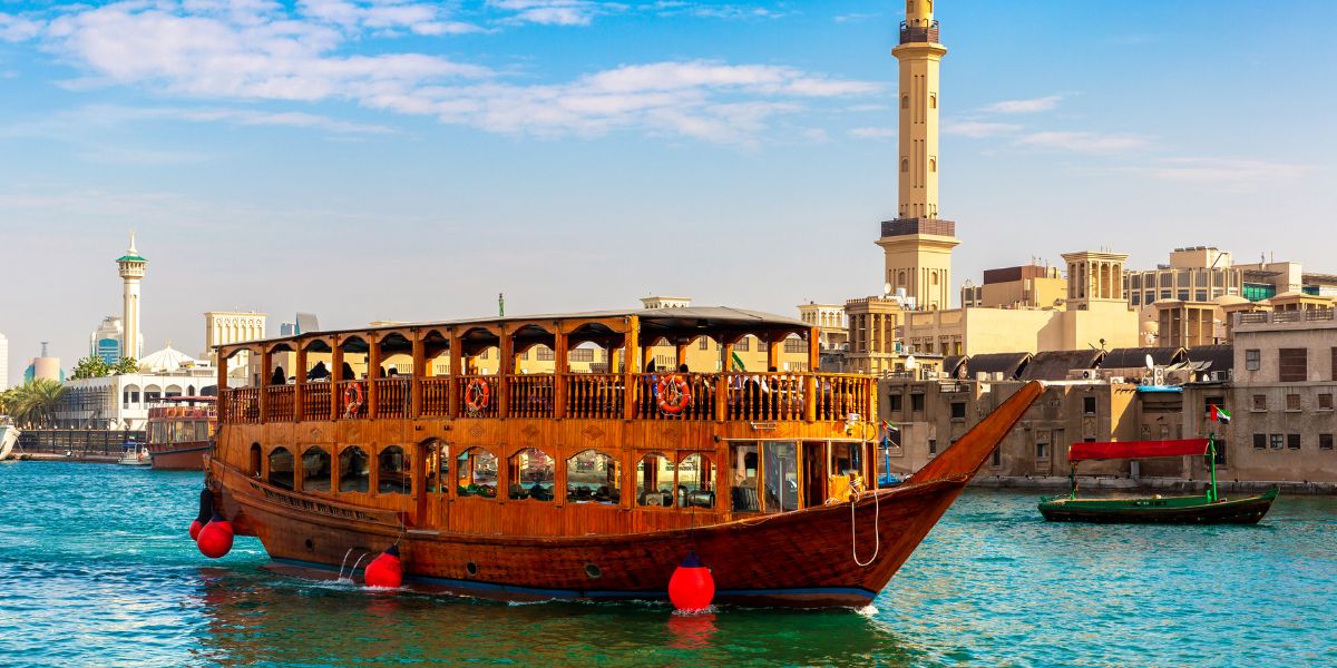 Dubai Creek dhow cruise with traditional wooden boat and old Dubai buildings