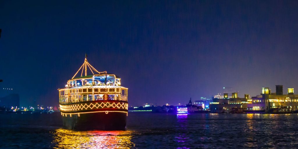 Dubai dhow cruise at night with illuminated traditional boat on water and city skyline